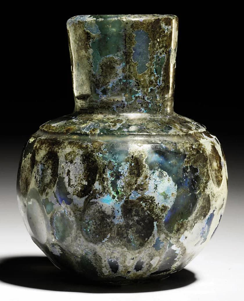 A FACET-CUT LIGHT GREEN GLASS BOTTLE